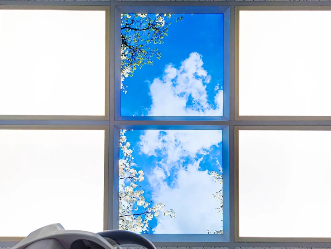 Moderne tandartsbehandelkamer bij Zahnarztpraxis Dr. Grünewald met heldere DL62 daglichtpanelen en rustgevend fotoplafond met natuurfoto’s.